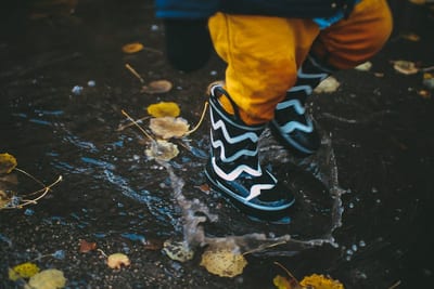A little kid splashing in the water in wellies in Rīgas pilsēta by Daiga Ellaby on Unsplash